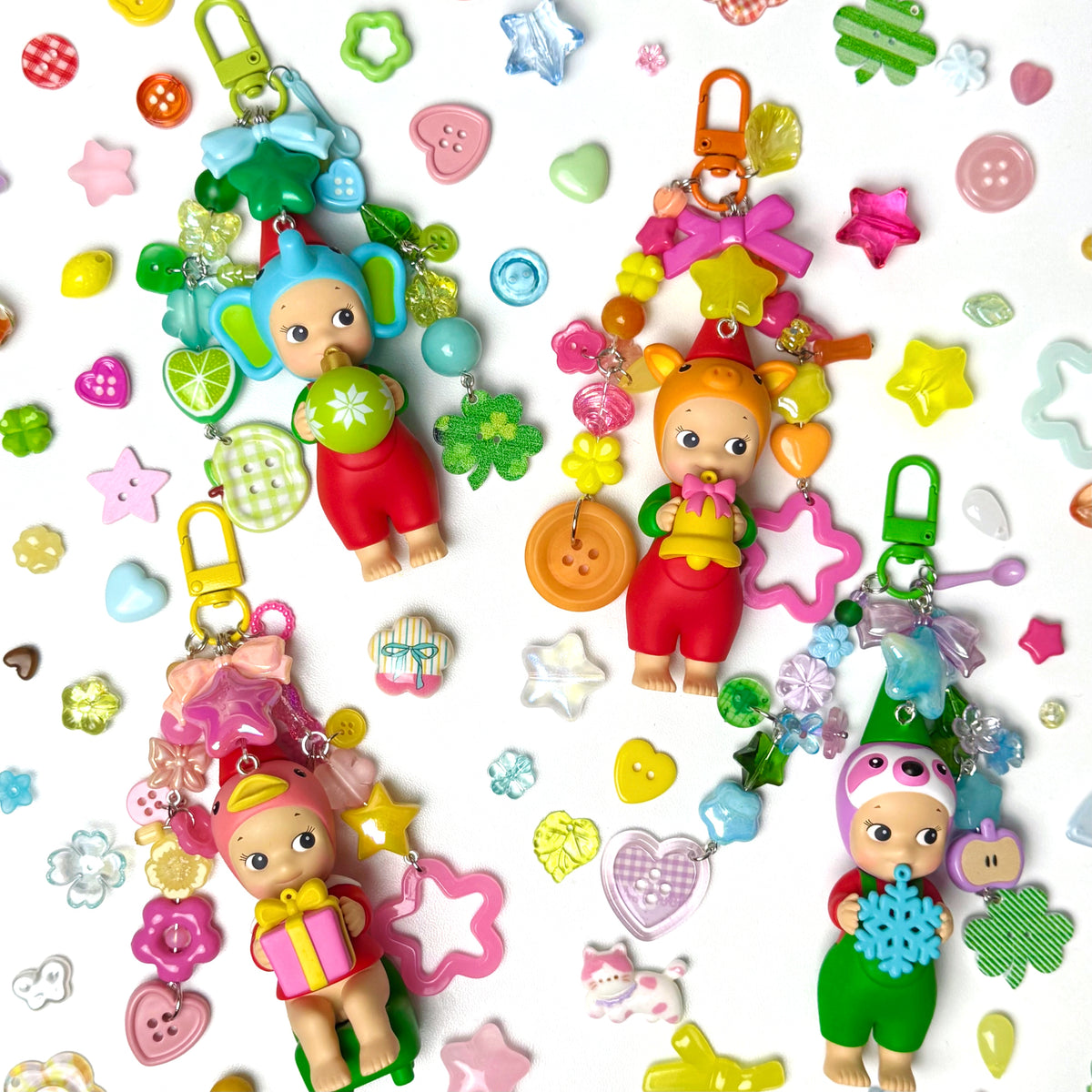 Colorful baby doll keychains with various accessories on a white background
