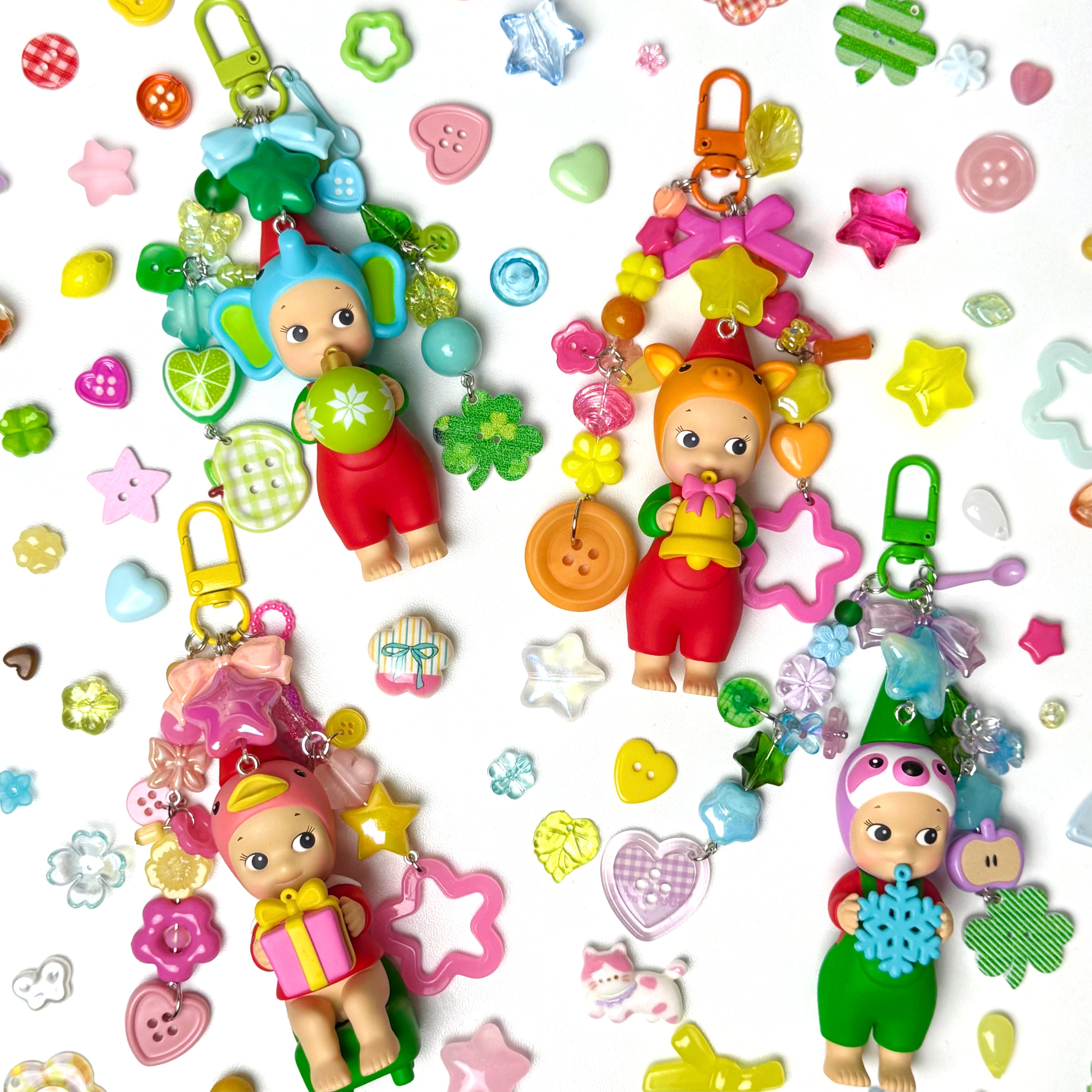 Colorful baby doll keychains with various accessories on a white background